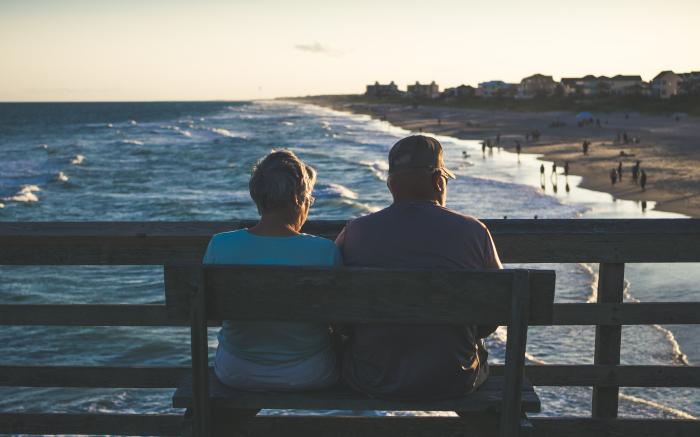 man and woman sitting on bench in front of beach by James Hose Jr courtesy of Unsplash.