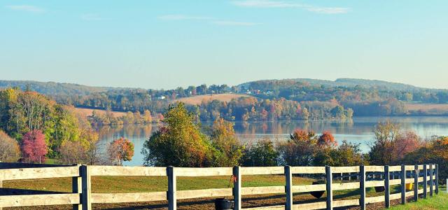 Beautiful autumn weather on a sunny day. Wooden fence along the country road.